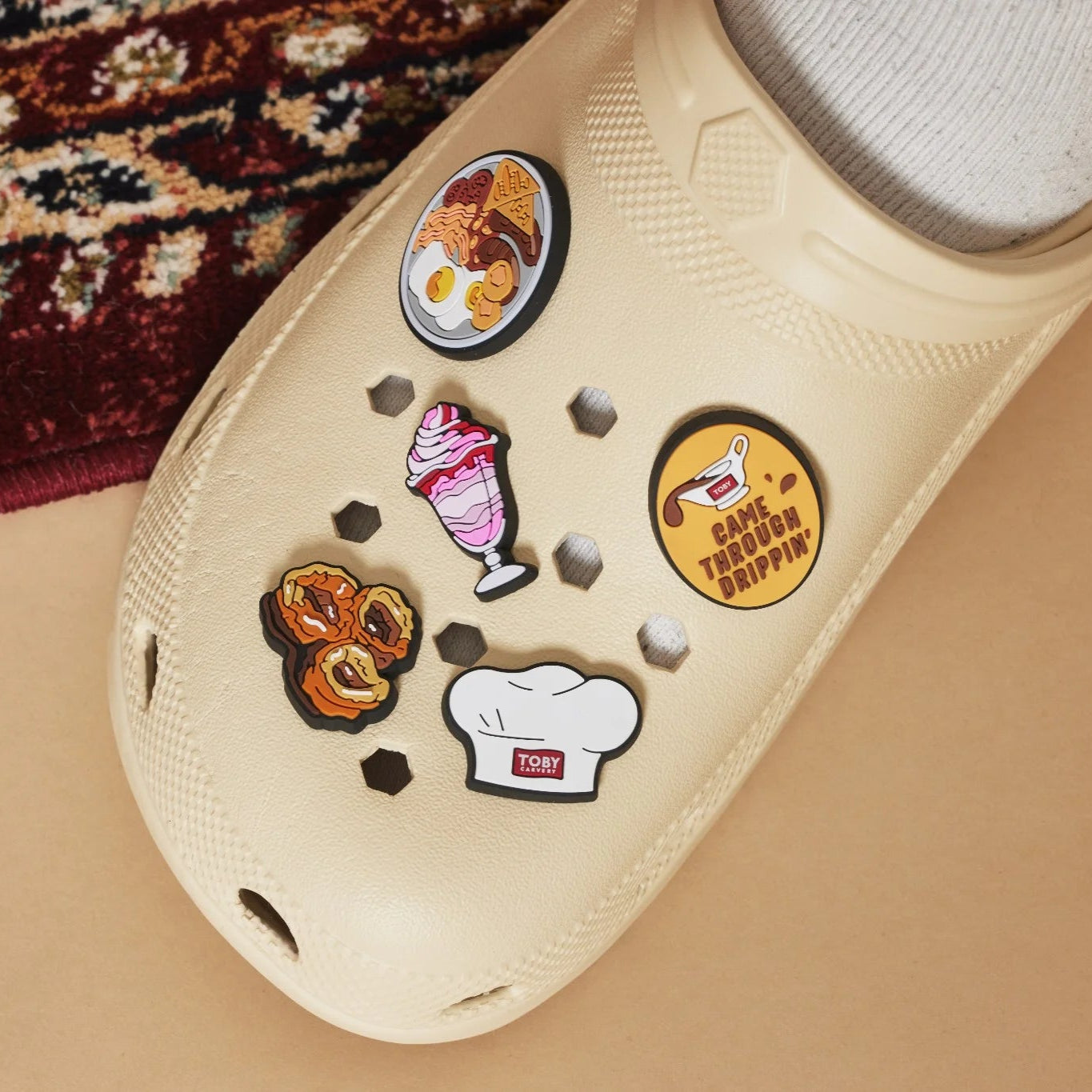 Beige clog with Toby Carvery shoe charms on a textured surface.