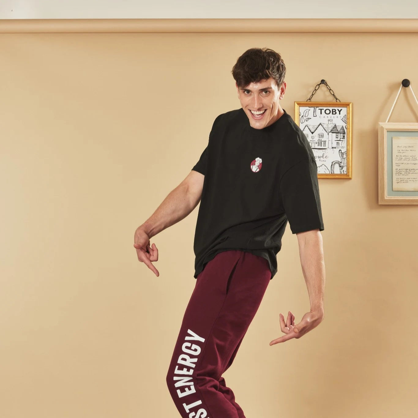 Person wearing a black t-shirt and burgundy joggers with 'Big Roast Energy' text, standing in a room.
