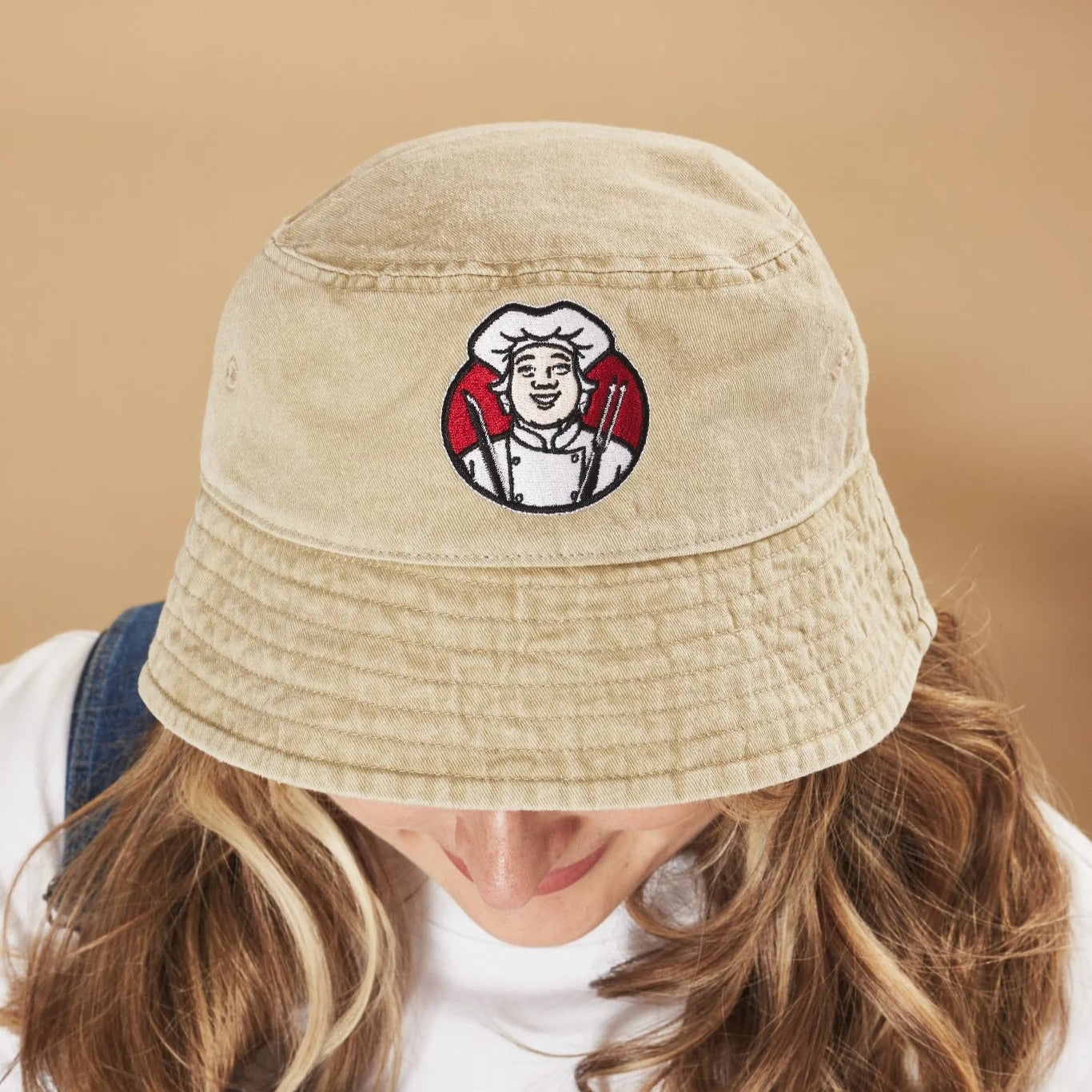 Oatmeal bucket hat with a Toby Carvery logo on a beige background