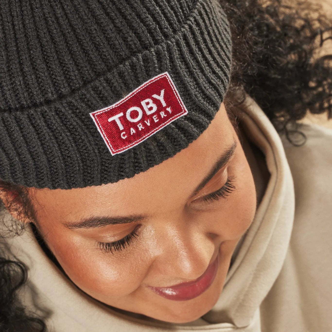 Person wearing a graphite beanie with a red 'Toby Carvery' logo.