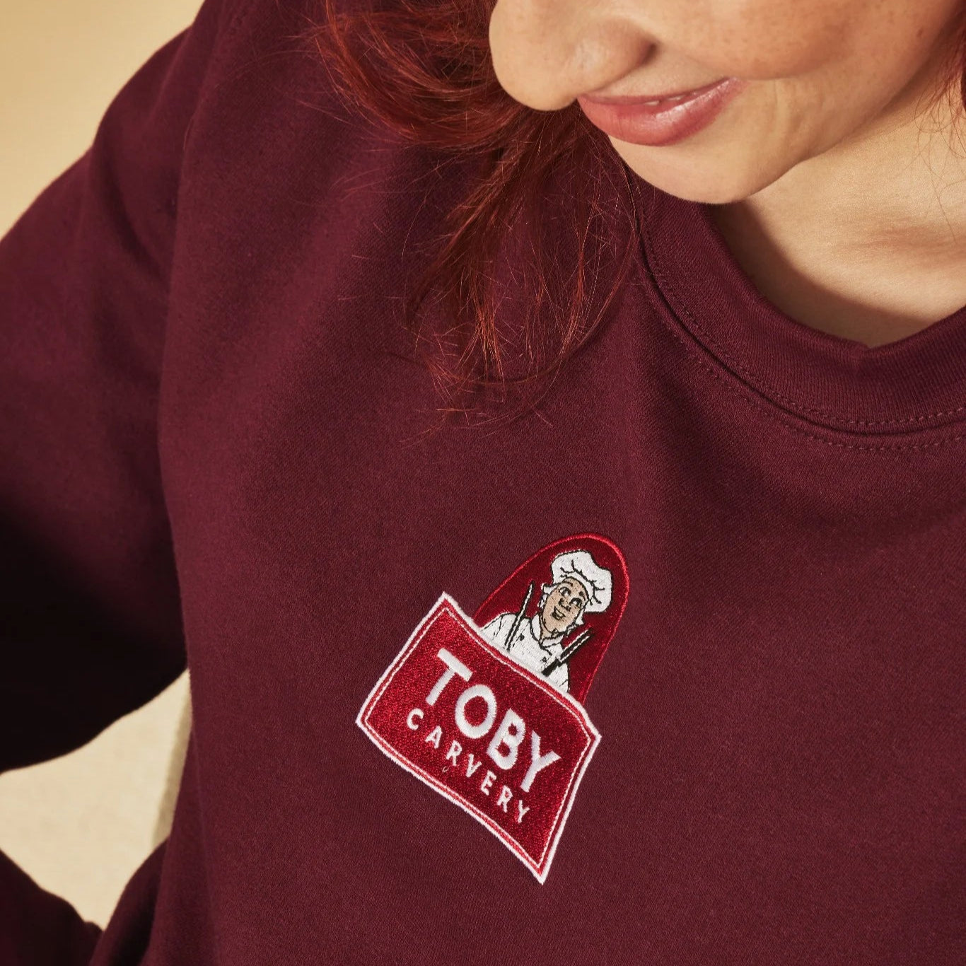 Person wearing a burgundy sweatshirt with a 'Toby Carvery' logo.
