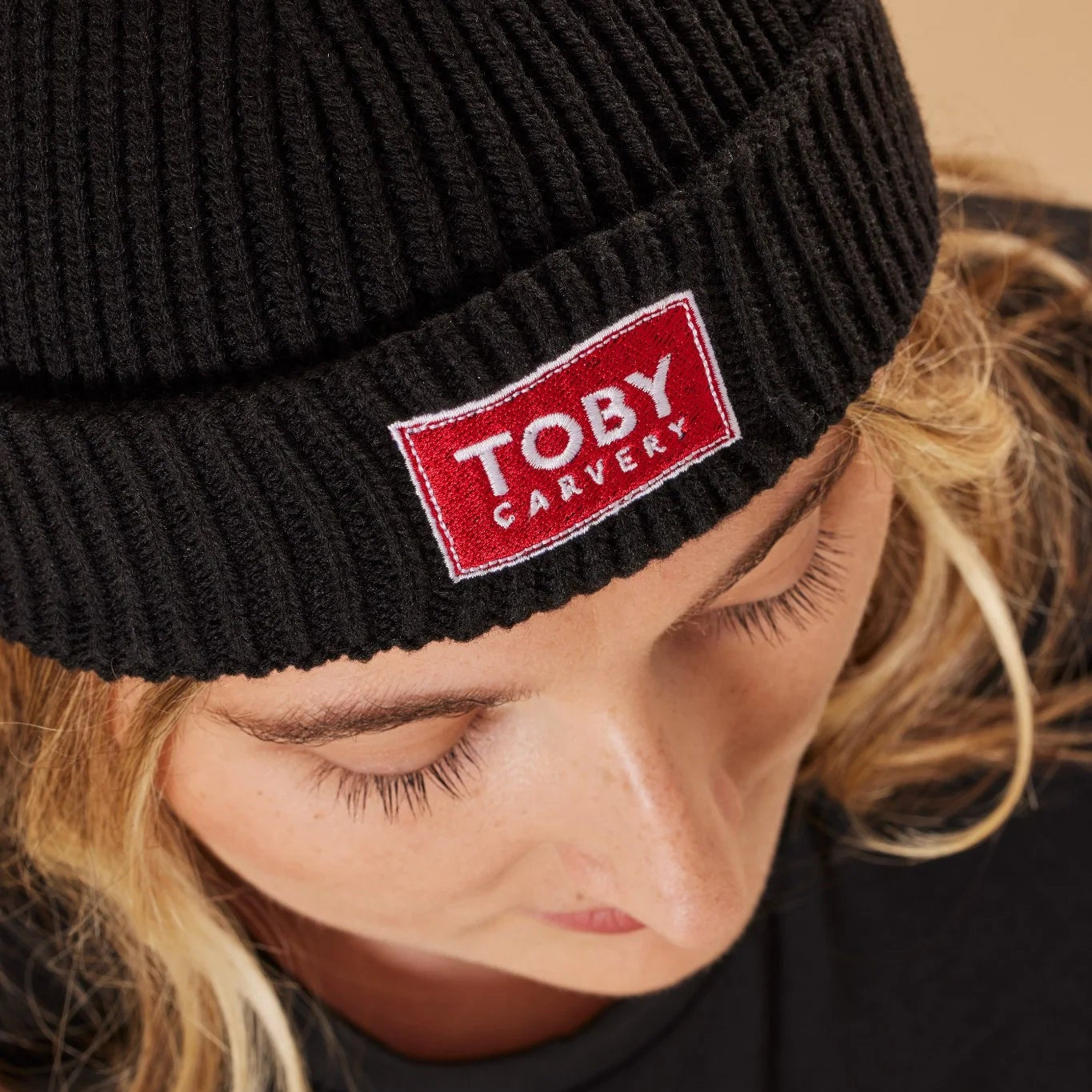 Person wearing a black beanie with a red 'Toby Carvery' logo.